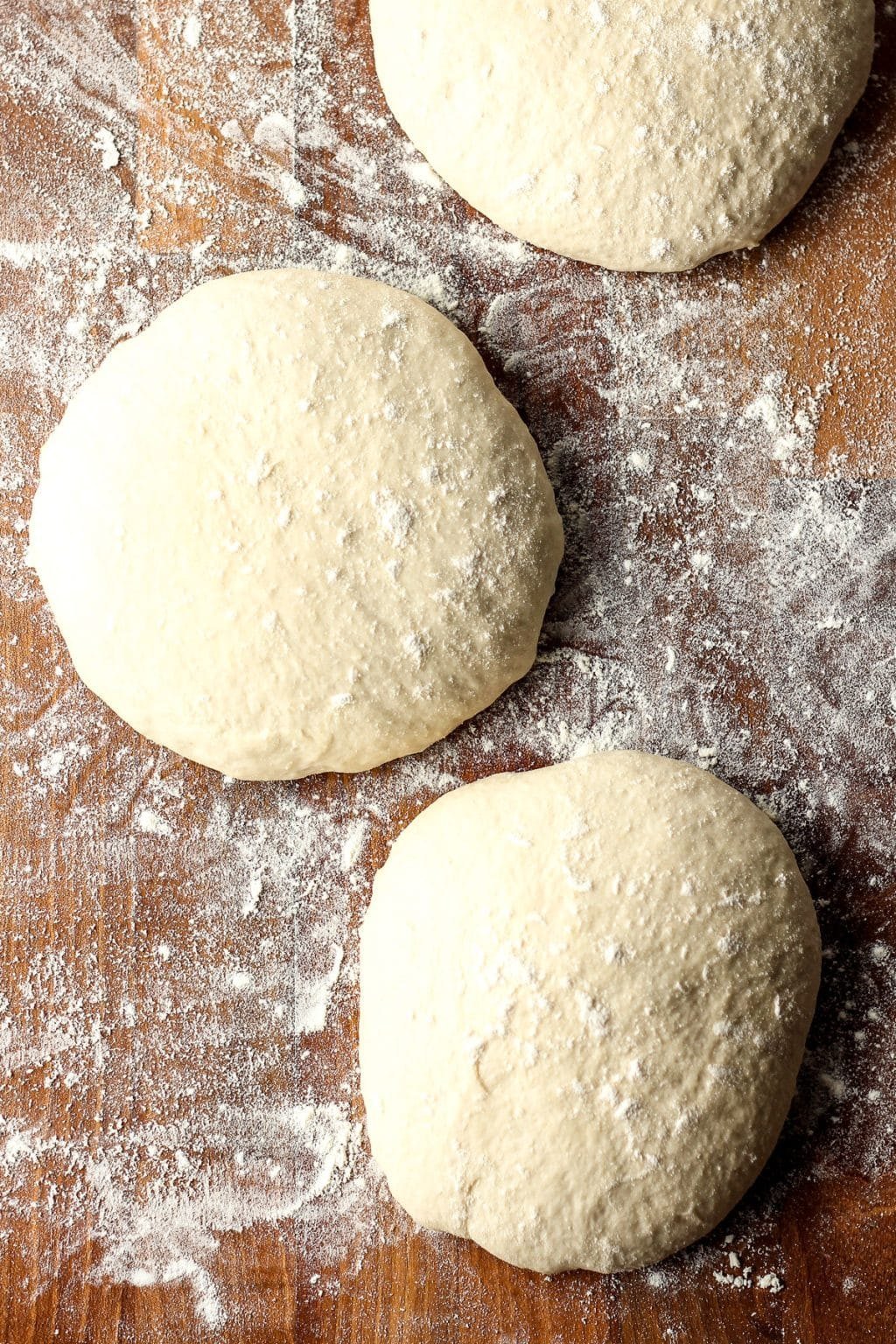 Proofed pizza dough ball on a floured board